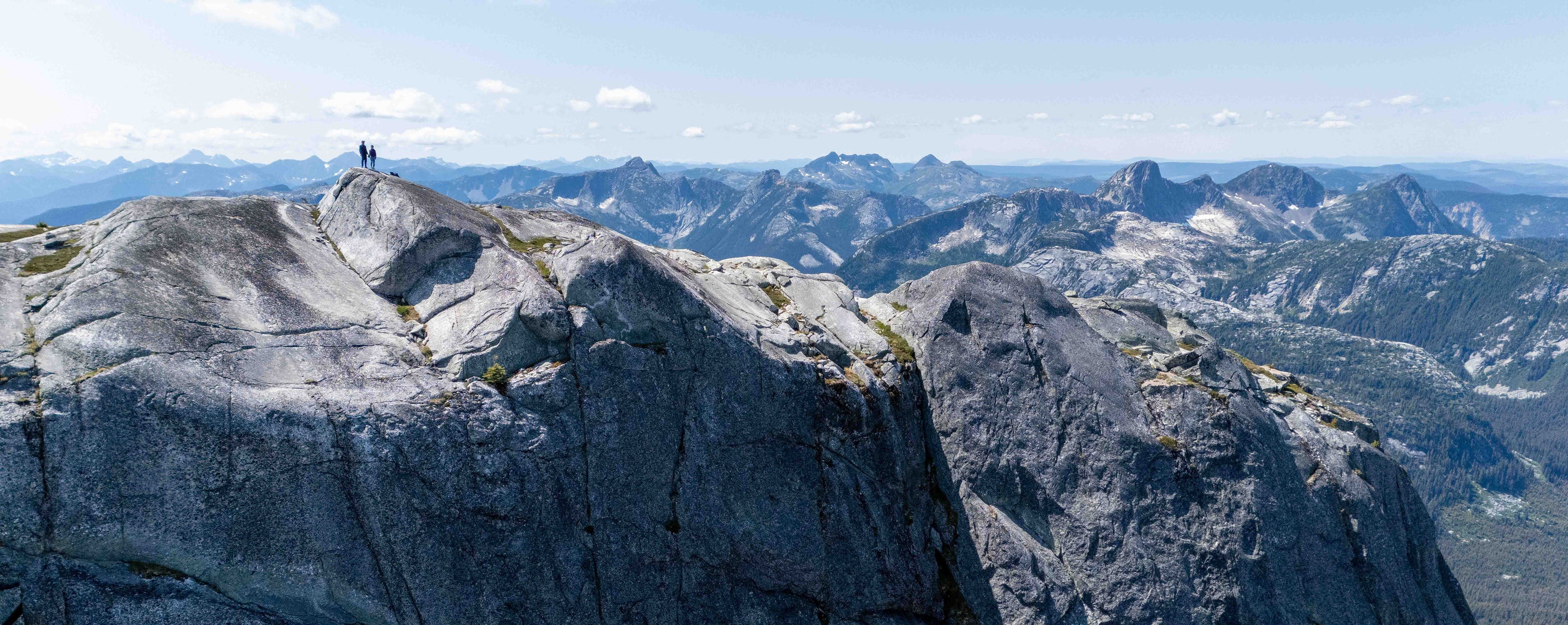 Two people standing on top of a mountain doing 3D photogrammetry 